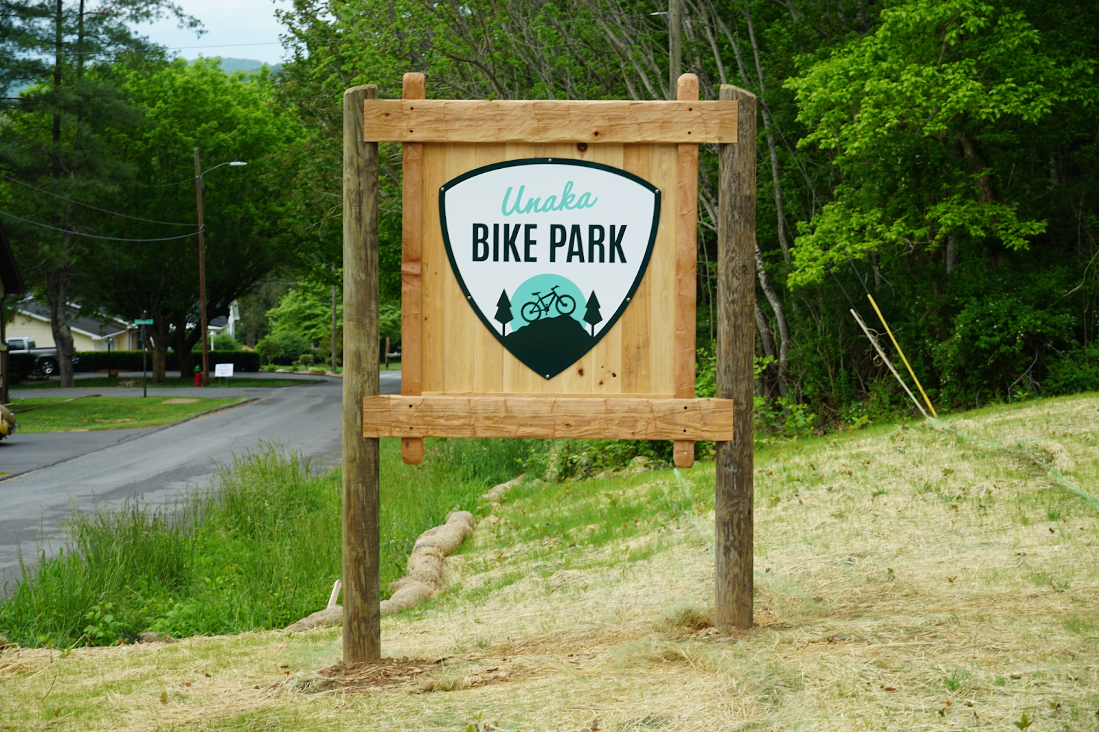 A rustic sign on the edge of a tree-covered mountainside announces the entrance to Unaka Bike Park