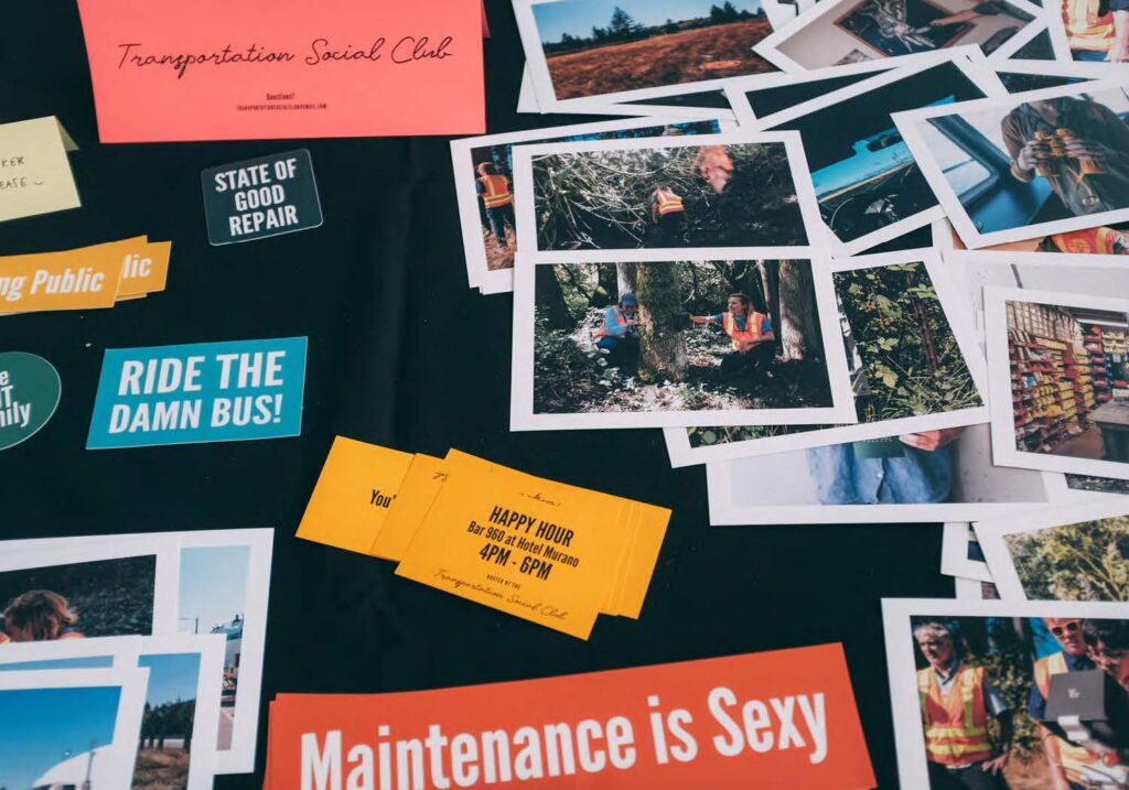 Image of the top of a table that has a black tablecloth. On top of the tablecloth is a variety of photos and bumperstickers that read 