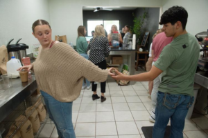 Teamwork is the name of the game as two high school students hand off duties while working in the coffee shop