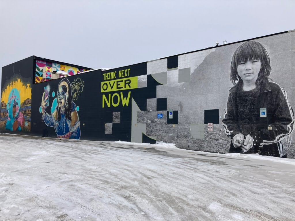 A snowy icy road with murals on buildings. 