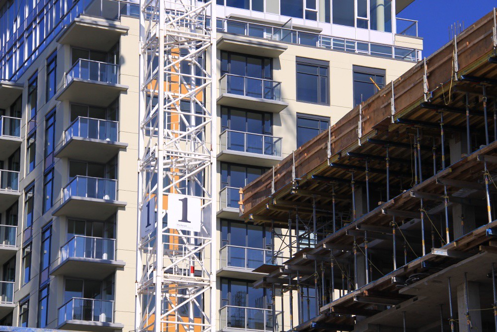 Mid-construction apartments rise into a blue sky