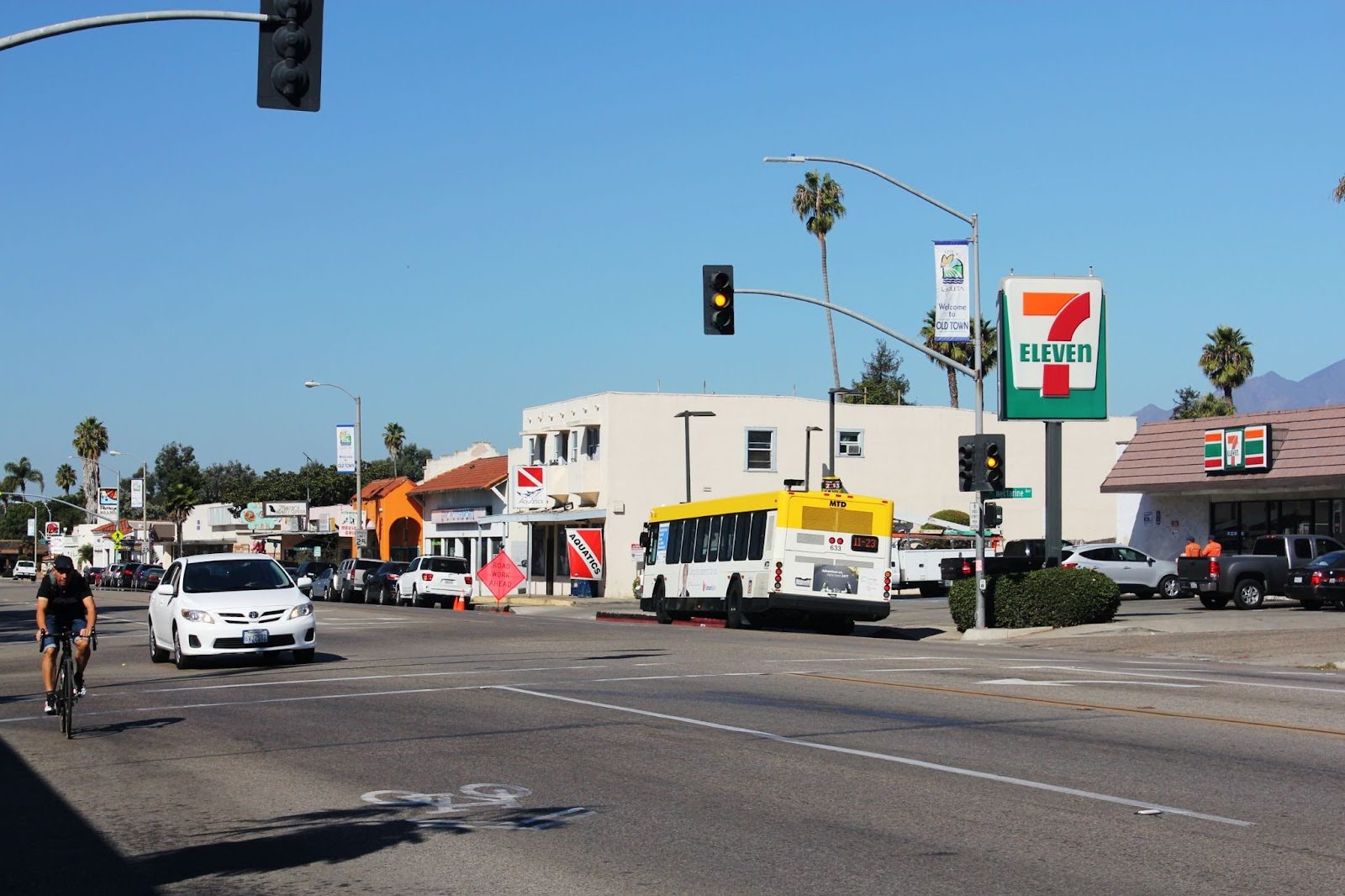 A busy city street includes a car, bus, and bicycle