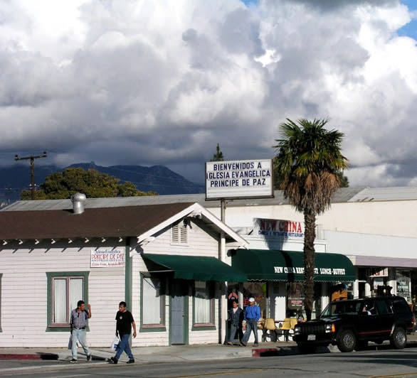 Pedestrians stroll across the street on their way to a cluster of shops in the project area