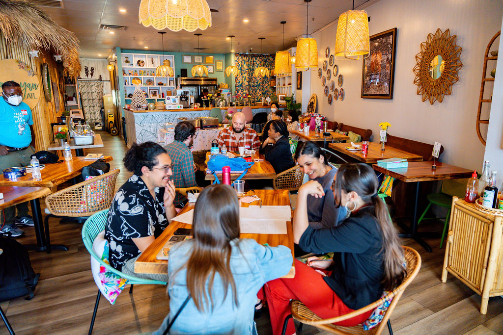A diverse group of individuals sitting around a restaurant table, laughing.