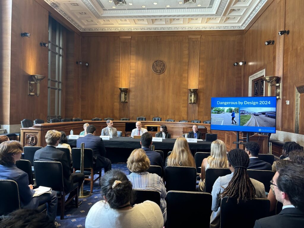 A panel sits before congressional staffers inside the US Capitol. A presentation on the right shows the words 