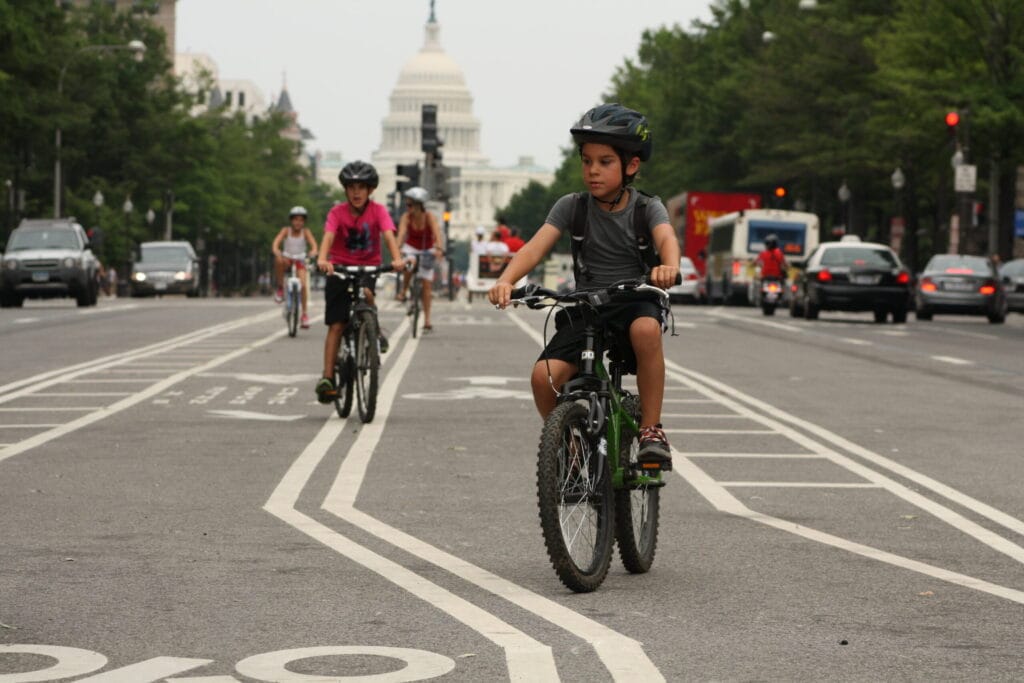 A group of children ride down the bike lane in front of the U.S. Capitol
